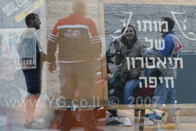 צלמי עתונות משתקפים בחלון התאטרון, משמאל לימין: ידיעות אחרונות, ידיעות חיפה מעריב ו  /כלבוynet  